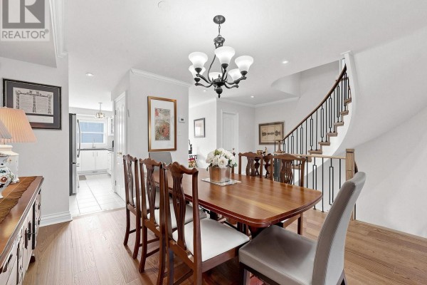 Dining room with a wooden table, chairs, chandelier, and a curved staircase. - 105 - 105 Leah Crescent, Vaughan