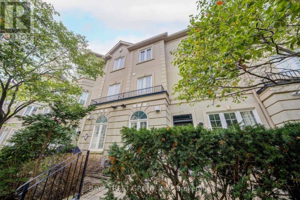 Facade of a beige townhouse with multiple windows, balconies, and decorative stonework. - 105 - 11 Everson Drive, Toronto