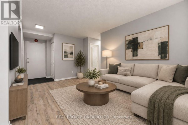 Living room with a large sectional sofa, coffee table, TV console, and light wood floors. - 105 - 2044 Arrowsmith Drive, Ottawa