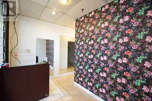 Reception area with a dark wood counter and a wall covered in floral patterned wallpaper. - 105 - 2347 Kennedy Road, Toronto