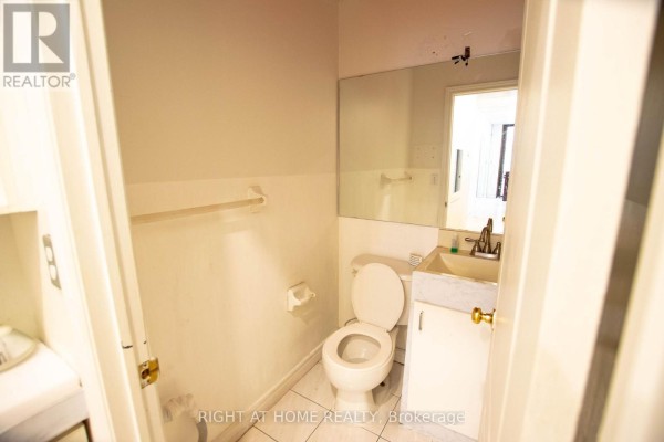 Small bathroom with a white toilet, sink, mirror, and towel rack on a pale yellow wall. - 105 - 2347 Kennedy Road, Toronto