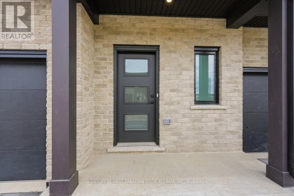 Close-up of a townhouse entrance with a black door, glass panels, and beige brick. - 105 - 2840 Buroak Drive, London North