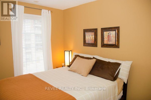 Bedroom with a queen-size bed, orange walls, and a window with white curtains. - 105 - 3 Everson Drive, Toronto