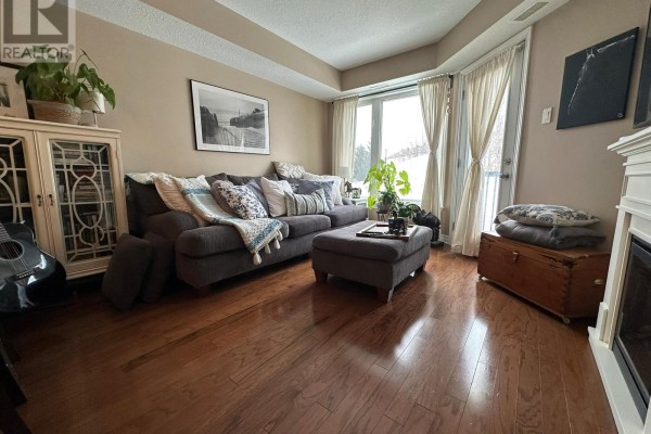 Living room featuring a gray sectional sofa, large windows, and hardwood flooring. - 105 - 398 Van Buren Street, North Grenville