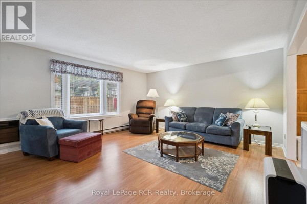 Living room with blue sofa, recliner, ottoman, coffee table, and wooden floor. - 105 - 497 Birmingham Street W, Wellington North