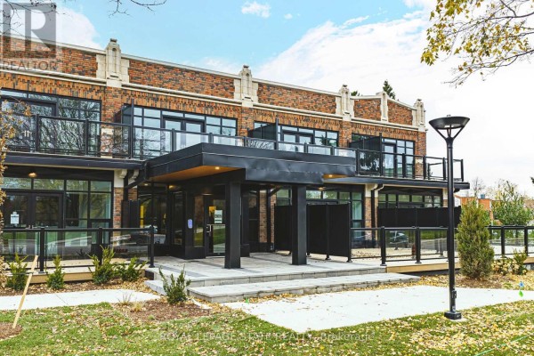 Close-up of the building's entrance with a modern black awning and glass doors. - 105 - 555 Sanatorium Road, Hamilton