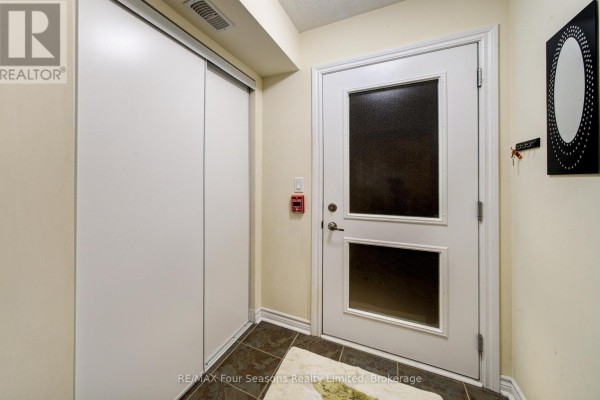 Interior apartment entryway with white door, closet, and decorative mirror. - 105 - 6 Brandy Lane Drive, Collingwood