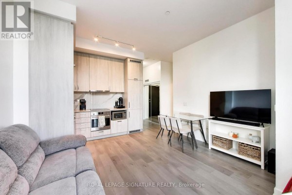 Open concept living and dining area with a grey sofa, glass dining table, and television. - 105 - 60 Honeycrisp Crescent, Vaughan
