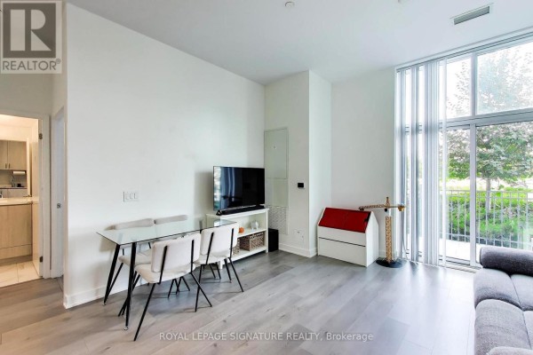 Dining area with glass table and chairs, television, and large window with balcony view. - 105 - 60 Honeycrisp Crescent, Vaughan