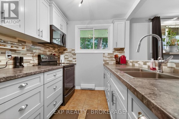 Kitchen with white cabinets, grey countertops, black stove, and mosaic tile backsplash. - 105 - 835 Milford Drive, Kingston