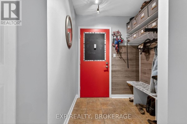 Entrance hallway with a red door, chalkboard, coat rack, and storage shelves. - 105 - 835 Milford Drive, Kingston