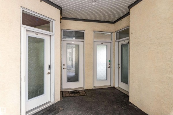 Covered exterior walkway with three frosted glass doors leading into apartments. - #105 10531 117 St Nw, Edmonton