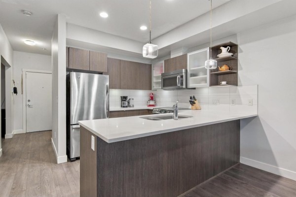 U-shaped kitchen with white quartz counters, stainless steel appliances, and dark wood cabinetry. - 105 19936 56 Avenue, Langley