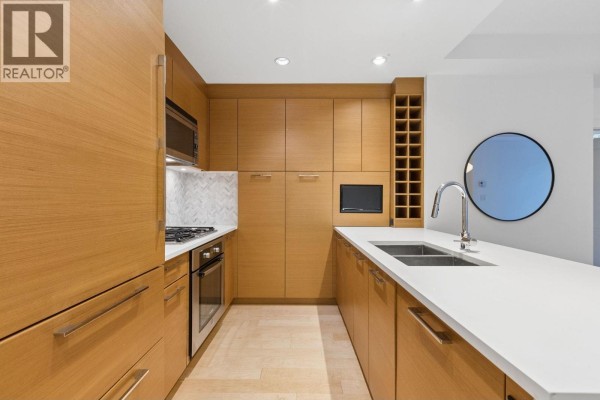 Modern kitchen with light wood cabinets, stainless steel appliances, and white quartz countertops. - 105 5868 Agronomy Road, Vancouver