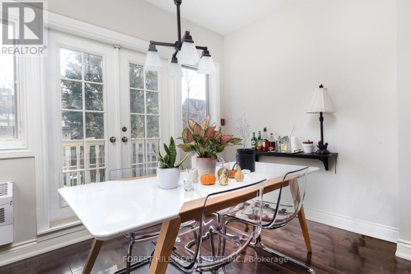 Dining area with a white table, clear chairs, and French doors opening to a balcony. - 105 Balmoral Avenue, Toronto