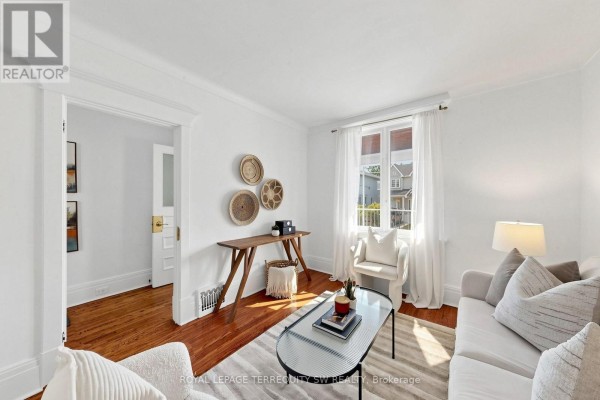 Empty living room with hardwood floors, white walls, and large window with curtains. - 105 Barker Avenue, Toronto