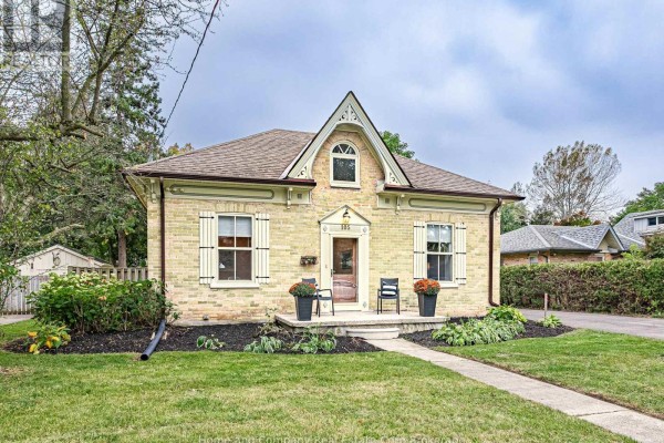 Side view of a light yellow brick house showing a paved driveway and mature trees. - 105 Centre Street, Stratford