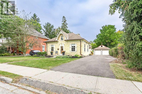 Street view of the yellow brick house with a black car parked in the driveway near the garage. - 105 Centre Street, Stratford