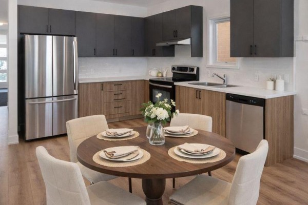 Open kitchen with stainless steel appliances, dark cabinets, and round dining table - 105 Creighton(lot 63) Drive, Loyalist