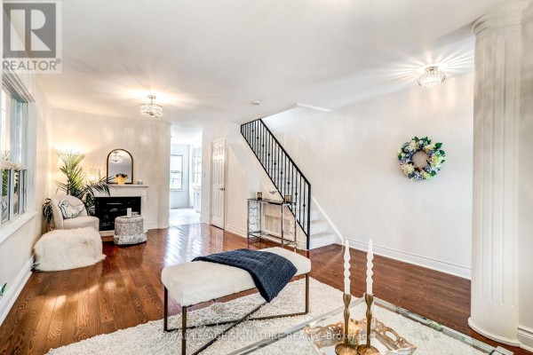 Living room with white walls, hardwood floors, fireplace, and decorative wreath. - 105 Earlscourt Avenue, Toronto
