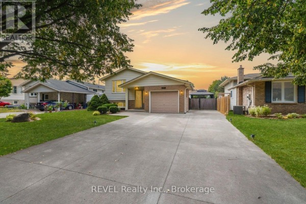 View of the bungalow from across the street with a long concrete driveway and mature trees. - 105 Elma Street, St  Catharines