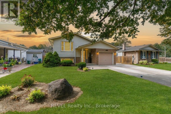 Side view of the bungalow showing the lawn, landscaping, and part of the garage. - 105 Elma Street, St  Catharines