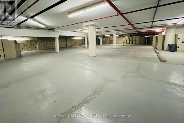 A large, unfinished commercial space with a grey concrete floor, overhead pipes, and lockers. - 105 Gordon Baker Road, Toronto