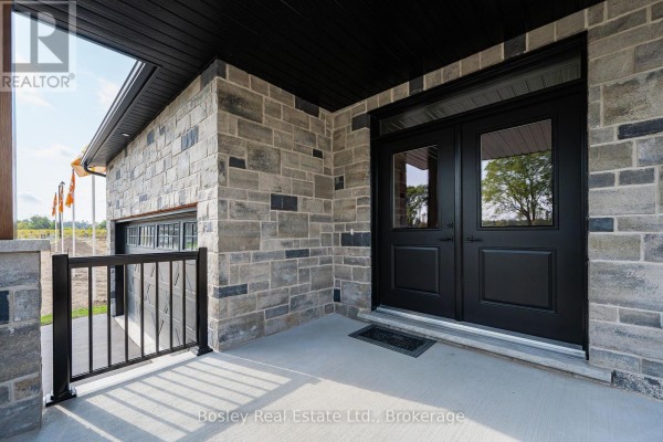 Close-up of the front door with double black doors and grey stone exterior walls. - 105 Haylock Avenue, Centre Wellington