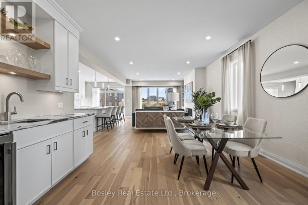 Open concept living and dining area with hardwood floors, white cabinets, and a large window. - 105 Haylock Avenue, Centre Wellington