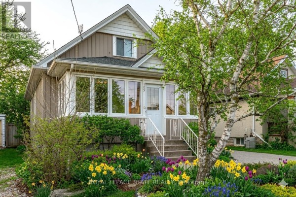 Sunroom interior with white-trimmed windows, dark blue paneled walls, and a white bench with pillows. - 105 Highland Avenue, St  Catharines