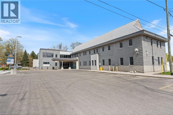 Side view of the Delhi Community Health Centre building showing brickwork and parking area. - 105 Main Street Unit# A, Delhi