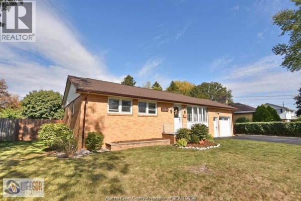 Finished basement with grey carpet, exposed wooden beams, laundry machines, and storage. - 1050 Scofield, Windsor