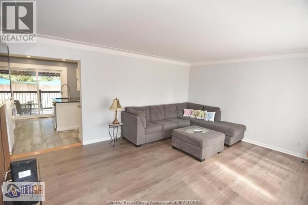 Spacious basement living area with two large grey sectionals, entertainment center, and television. - 1050 Scofield, Windsor