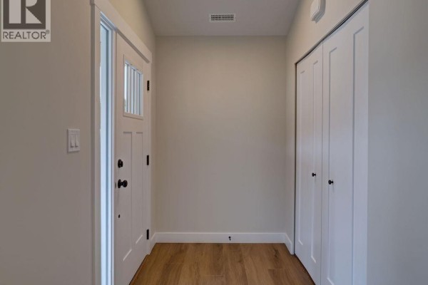 Open concept living room and kitchen with vaulted ceiling, white cabinets, island, and light wood flooring. - 1051 Celia Crescent, Gibsons