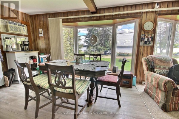 Dining table set with placemats in a room with wood paneling and bay window view. - 1051 Halls Lake Road, Algonquin Highlands