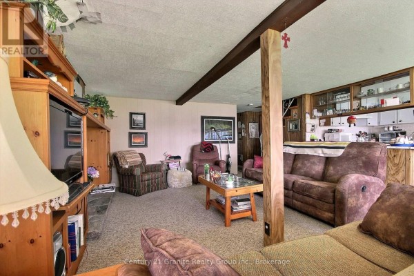 Living room with sofas, chairs, coffee table, and built-in entertainment unit. - 1051 Halls Lake Road, Algonquin Highlands