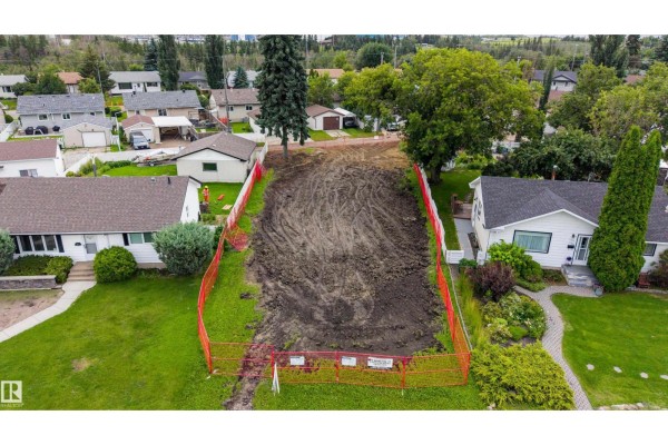 A cleared building lot surrounded by orange safety fencing with adjacent houses. - 10513 42 St Nw, Edmonton