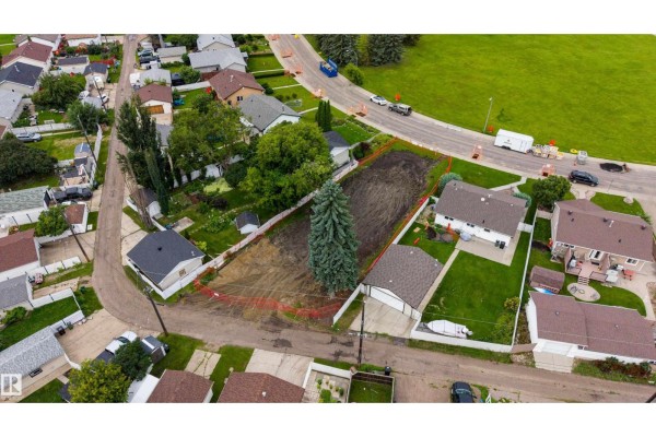Aerial view of a leveled building lot with orange fencing and surrounding homes. - 10513 42 St Nw, Edmonton