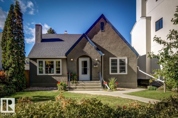 Front of a stucco house with a pitched roof and a white front door under a bright sky. - 10514 127 Street Nw, Edmonton