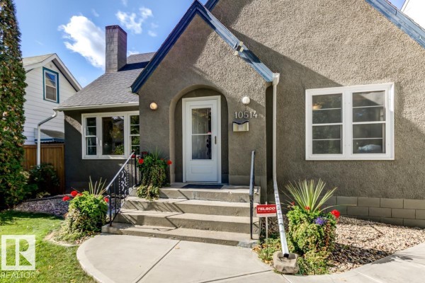 Close-up of the front entrance of a stucco house with a white door and stairs. - 10514 127 Street Nw, Edmonton