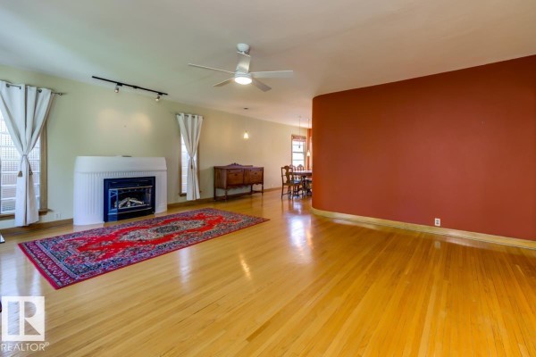 Living room with hardwood floors, a fireplace, and a dining area with a round table. - 10514 127 Street Nw, Edmonton