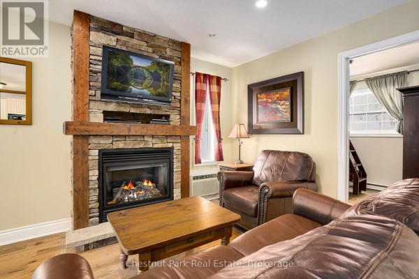 Living room fireplace with stone surround, television, and comfortable seating. - 1052 Rat Bay 103-1 Road, Lake Of Bays