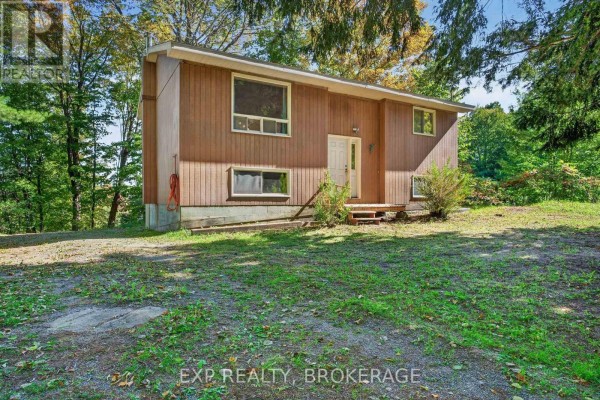Side view of a light brown wood-sided house with a small wooden porch. - 1054 York Road, Frontenac
