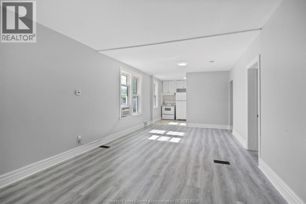 Interior living area with light grey walls, laminate flooring, and an open kitchen. - 1056-1060 Niagara, Windsor