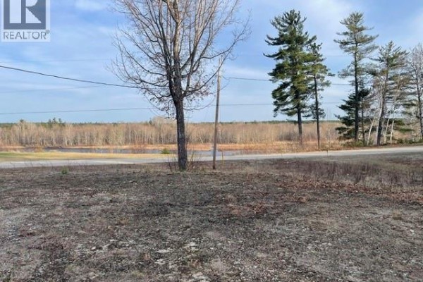 Aerial view of the property and neighboring structures on a tree-lined dirt road. - 1056 Halcomb Road, Halcomb