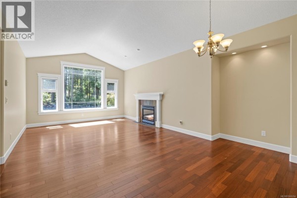 Living and dining room with hardwood floors, vaulted ceiling, and gas fireplace. - 1057 Paradise Pl, Nanoose Bay