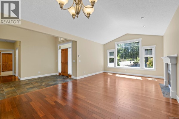 Open-concept living area with hardwood floors, stone entryway, and large window view. - 1057 Paradise Pl, Nanoose Bay