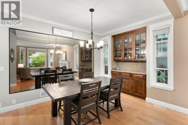 Formal dining room with a large mirror, dark wood table, and buffet cabinet. - 10574 239 Street, Maple Ridge