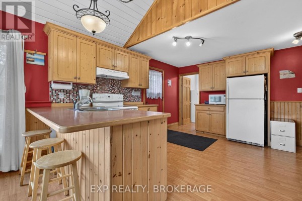 Wooden deck with rustic railings overlooking a green treed landscape. - 1058 Perry Road, Frontenac