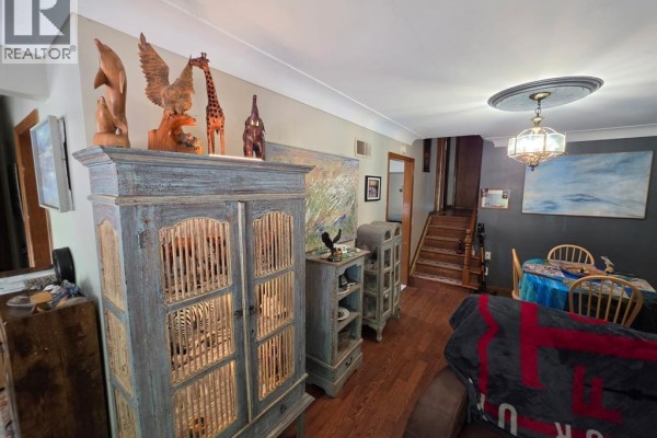 Living room with wood floors, decorative cabinets, staircase, and dining area. - 1058 Riverdale, Windsor